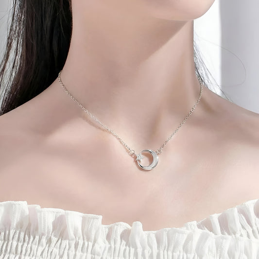 Silver necklace with a circular pendant on a model wearing a white top.