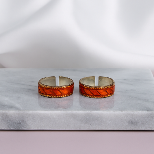 Two orange and silver rings on a marble stand with a white fabric background