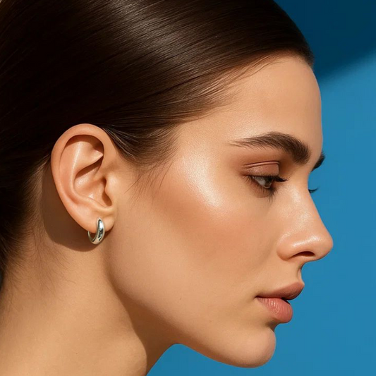 Woman with a ponytail wearing an earring against a blue background
