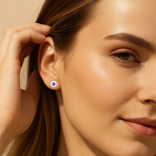 Close-up of a woman wearing a purple gemstone earring against a neutral background