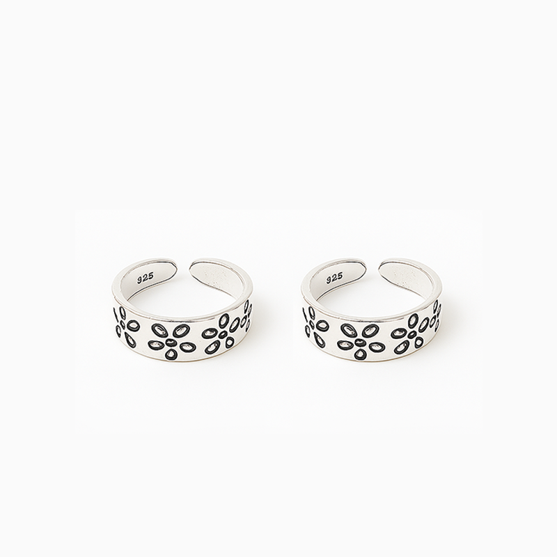 Two silver open rings with floral patterns on a white background