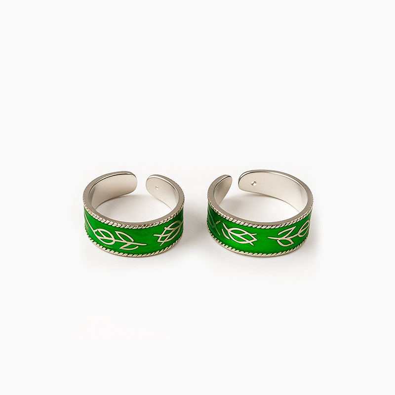 Two green and silver leaf-patterned rings on a white background