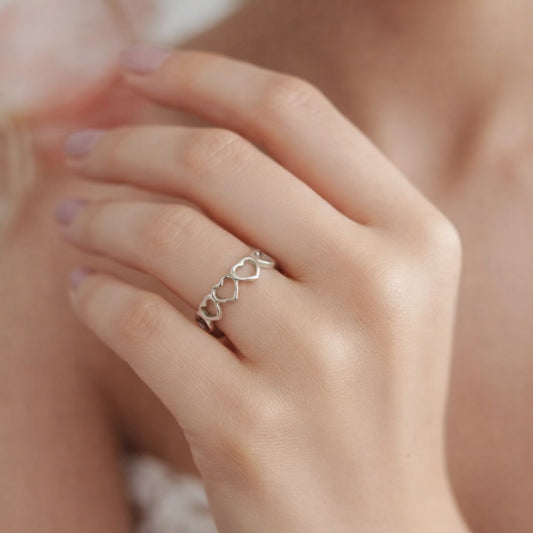 Silver ring with a unique design on a person's finger against a blurred background
