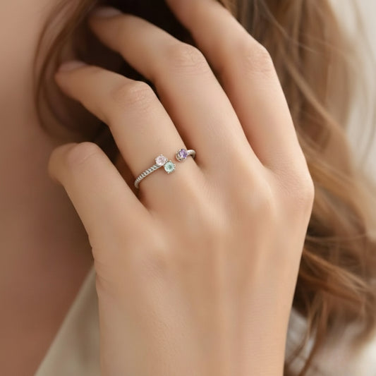 Close-up of a hand wearing two rings with gemstones, one pink and one multicolored.