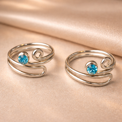 Two silver rings with blue gemstones on a beige fabric background