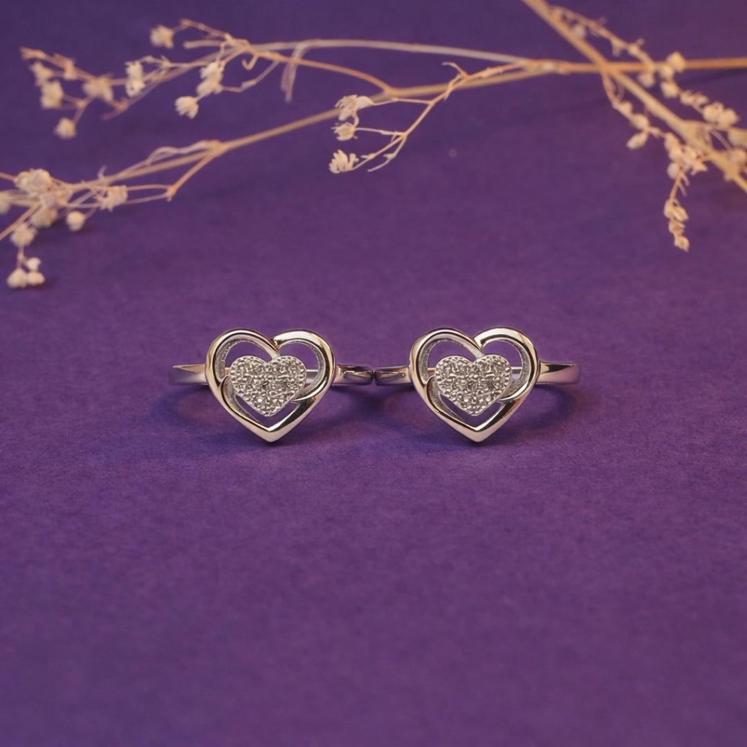 Heart-shaped gold rings on a purple background with dried flowers.