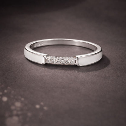 Silver ring with embedded diamonds on a dark background