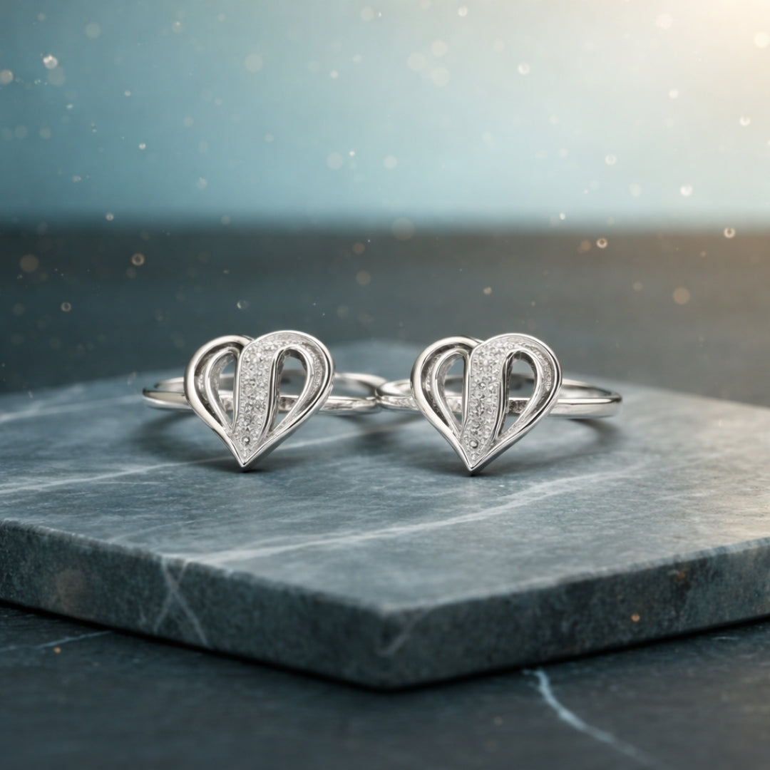 Pair of silver heart-shaped earrings on a dark marble surface with a blurred light background