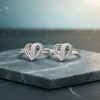 Pair of silver heart-shaped earrings on a dark marble surface with a blurred light background