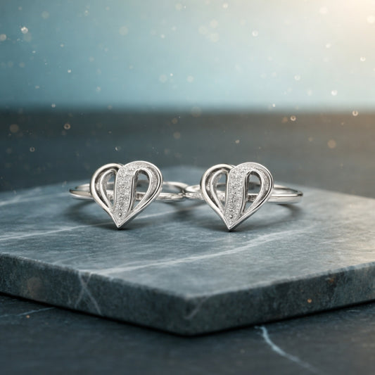 Pair of silver heart-shaped earrings on a dark marble surface with a blurred light background