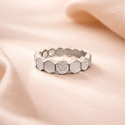 Silver ring with hexagonal gemstones on a soft pink fabric background