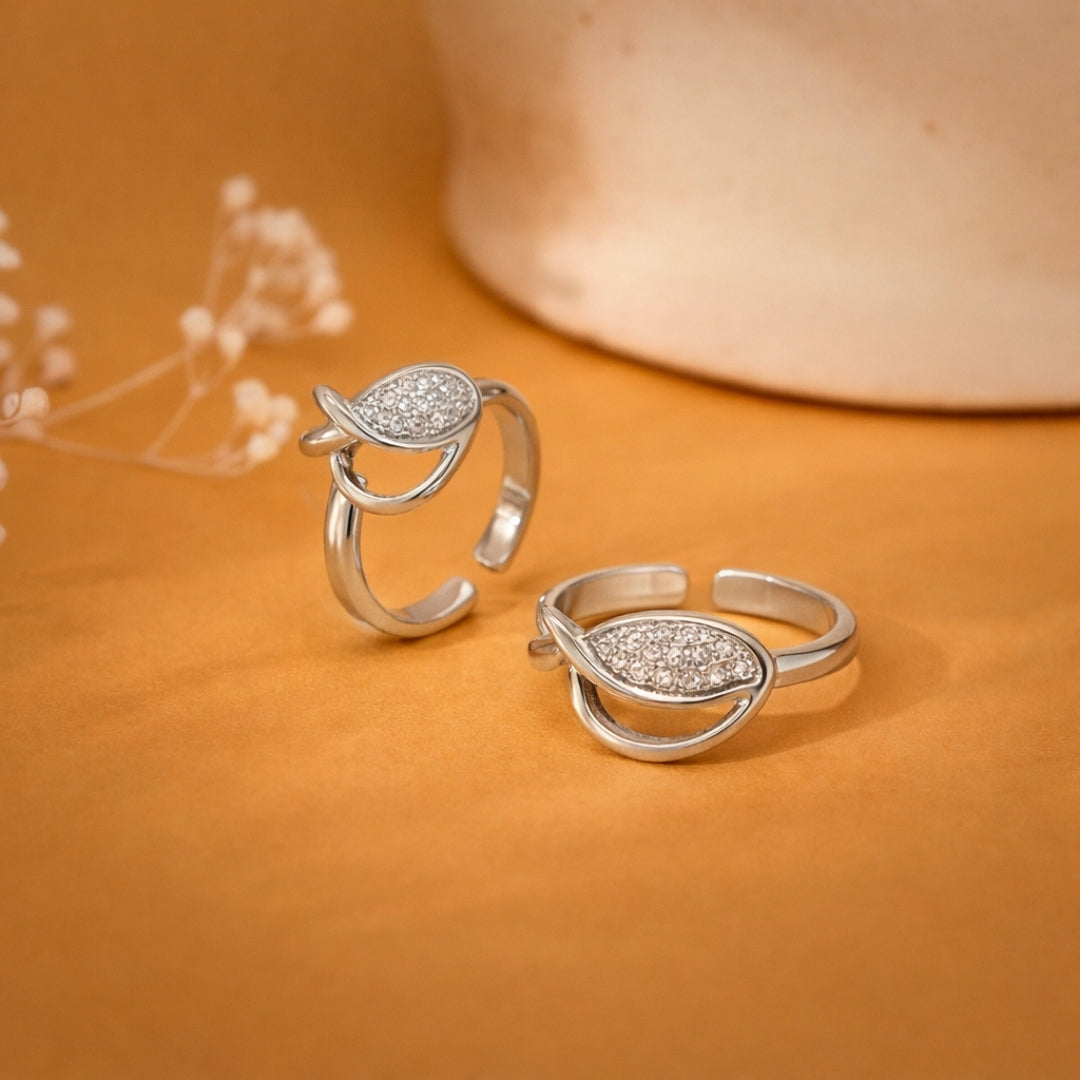 Pair of silver rings with teardrop design on an orange background