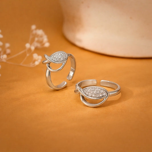 Pair of silver rings with teardrop design on an orange background