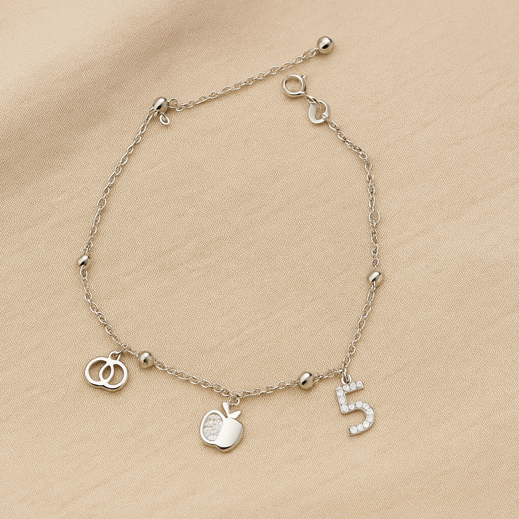 Silver bracelet with charms on a beige fabric background