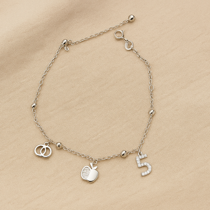 Silver bracelet with charms on a beige fabric background