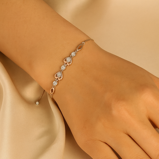 Gold bracelet with heart-shaped charms on a wrist against a beige background