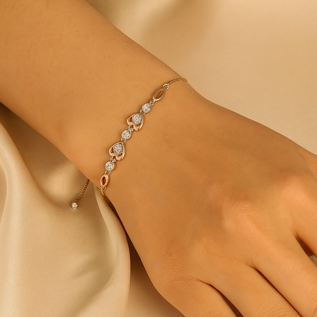 Gold bracelet with heart-shaped charms on a wrist against a beige background