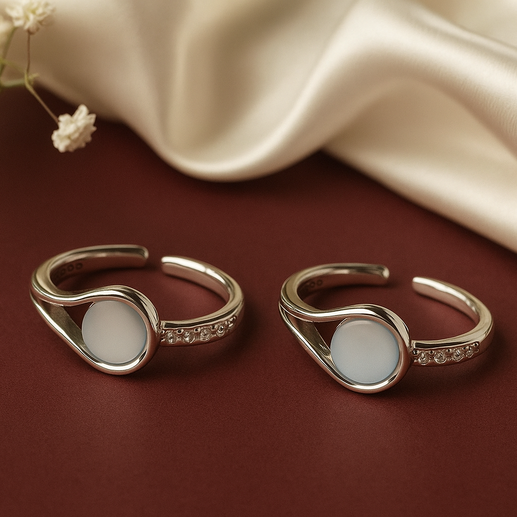 Two gold rings with white stones on a brown surface with a beige fabric background.