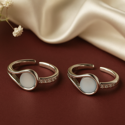 Two gold rings with white stones on a brown surface with a beige fabric background.