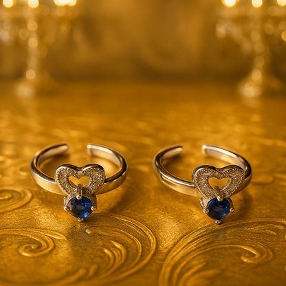 Two heart-shaped rings with blue gemstones on a gold background