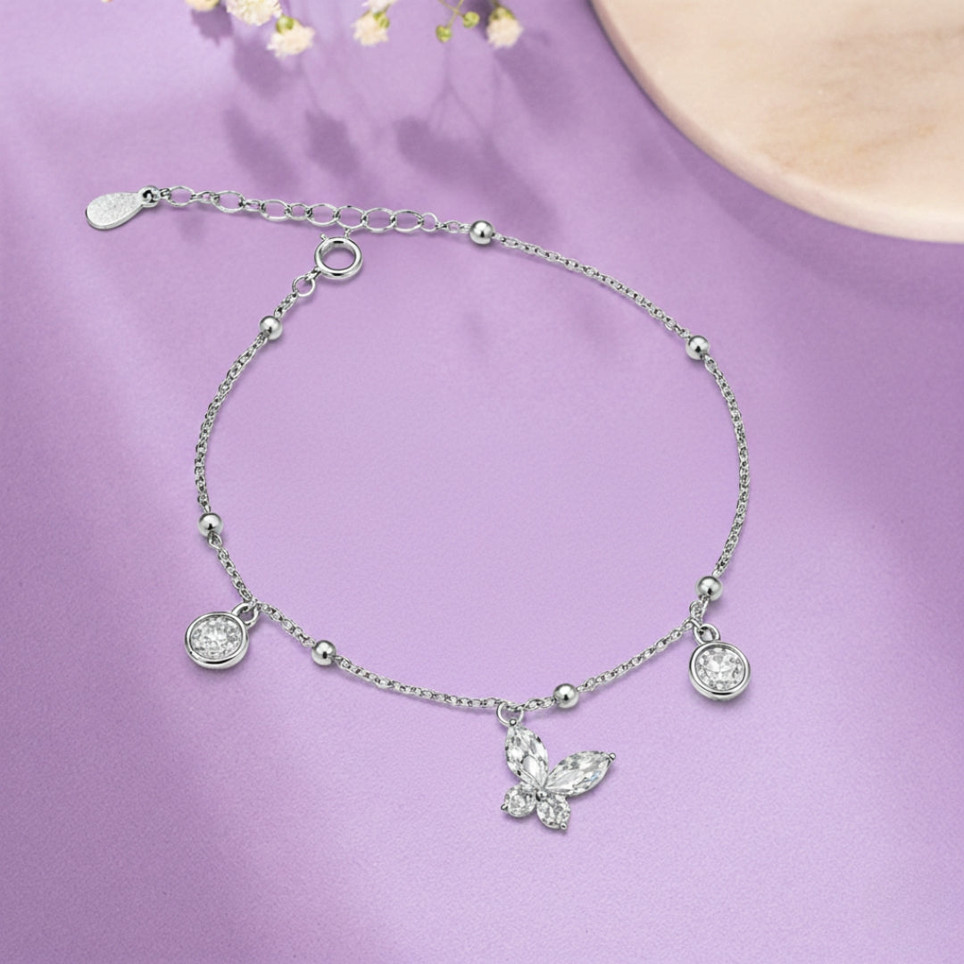 Silver bracelet with a butterfly charm on a purple background