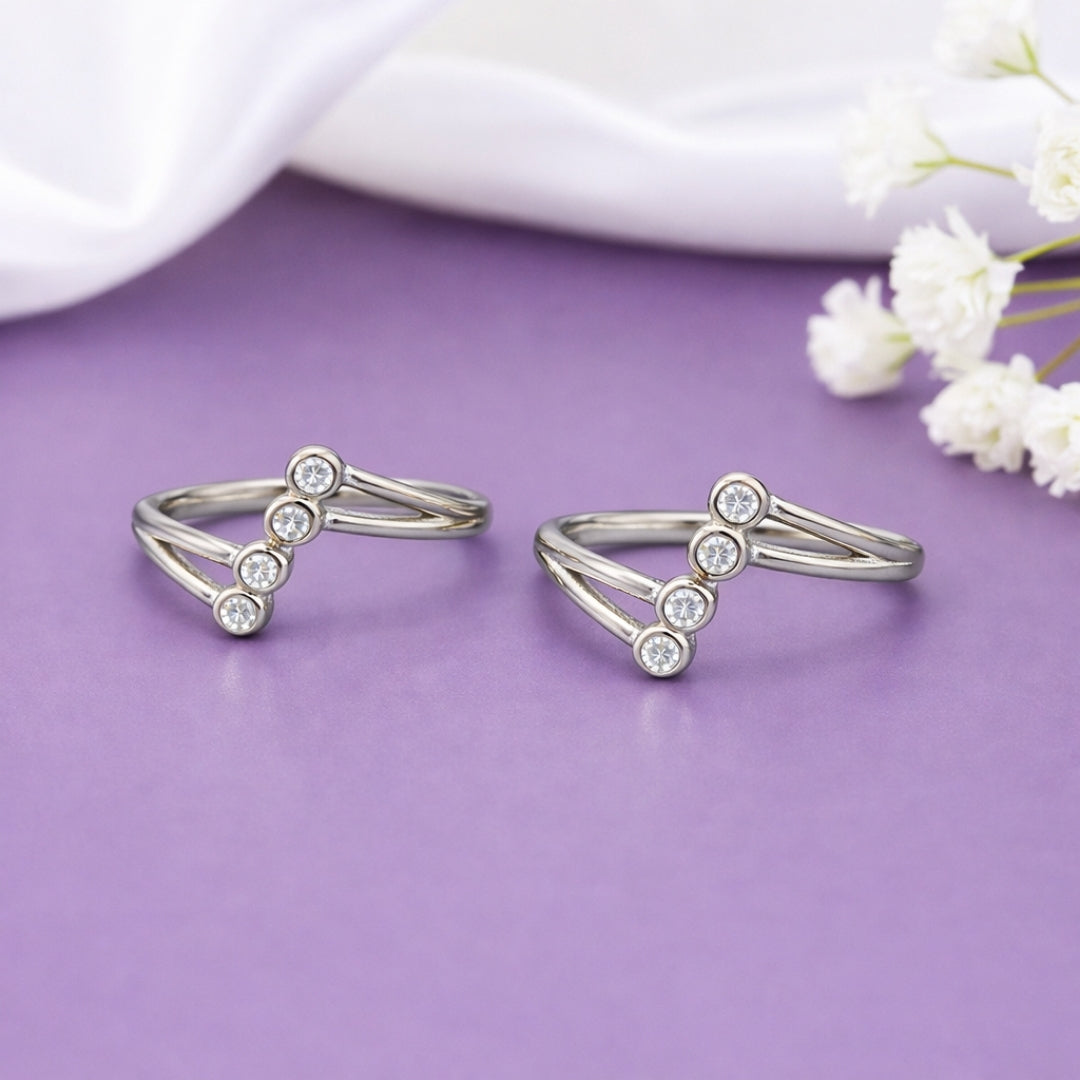 Two silver rings with small diamonds on a purple surface with white flowers.