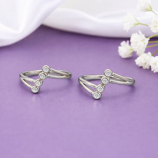 Two silver rings with small diamonds on a purple surface with white flowers.