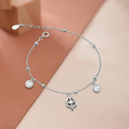 Silver bracelet with clover charm on a two-tone background