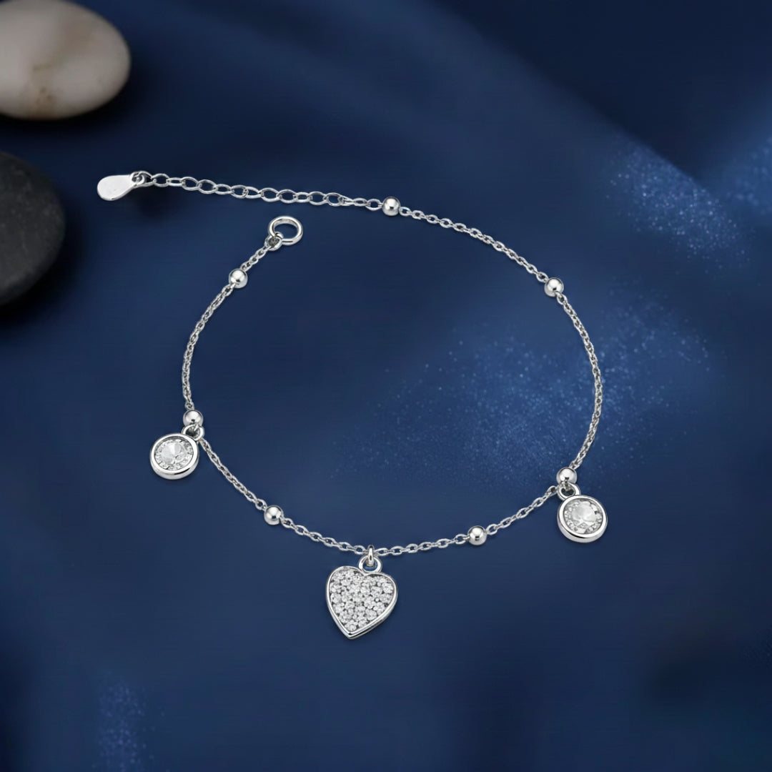 Silver bracelet with heart charm on a dark blue background