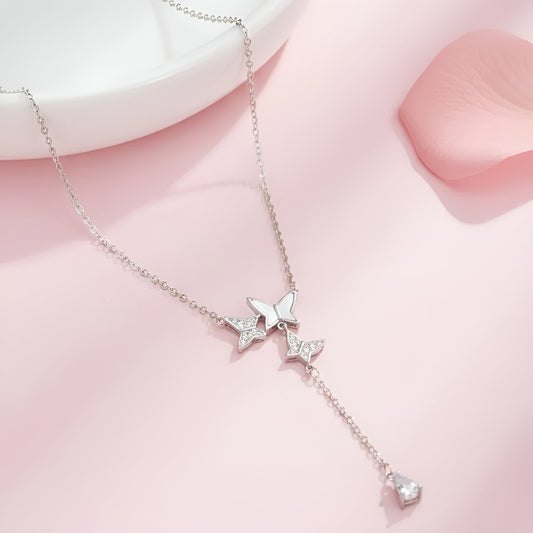 Silver butterfly necklace on a pink fabric background