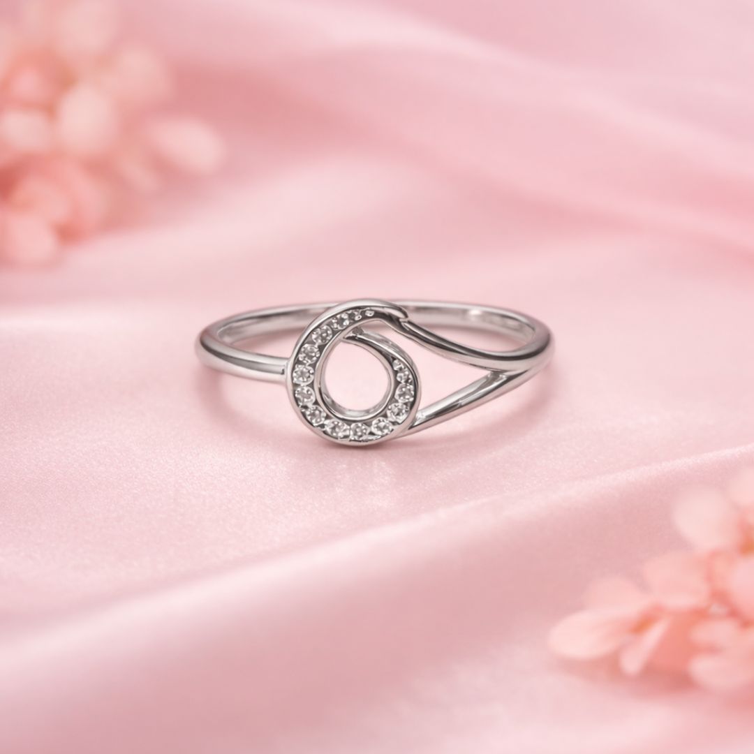 Silver ring with a circular design on a pink satin background