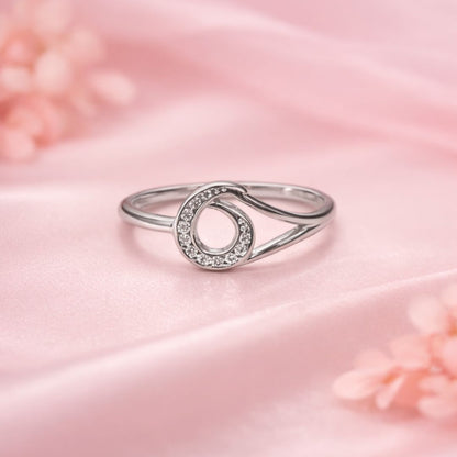 Silver ring with a circular design on a pink satin background