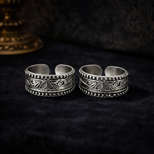 Two silver rings with intricate designs on a dark background