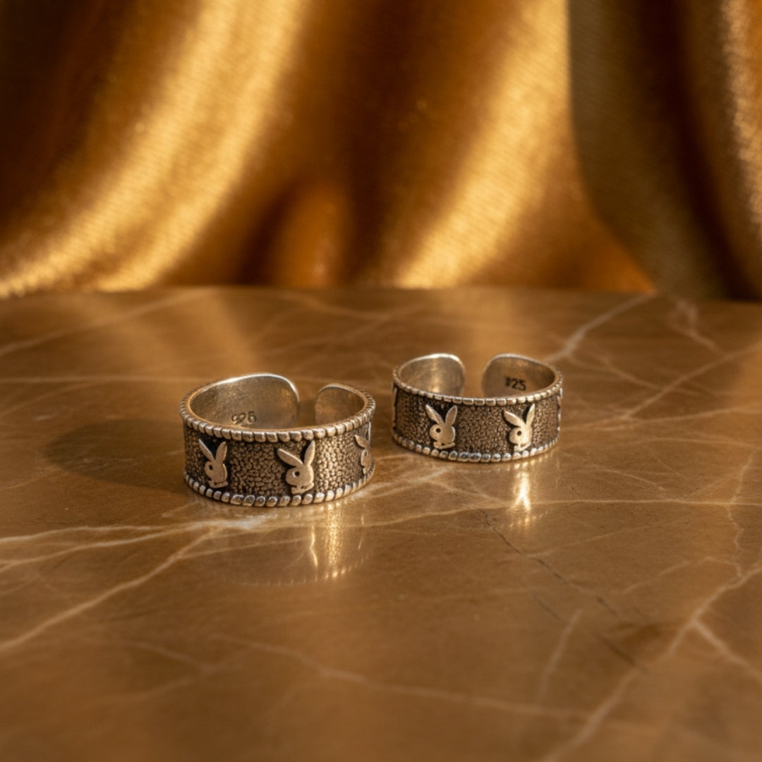 Two silver ear cuffs with rabbit design on a textured brown surface