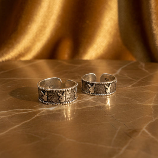 Two silver ear cuffs with rabbit design on a textured brown surface