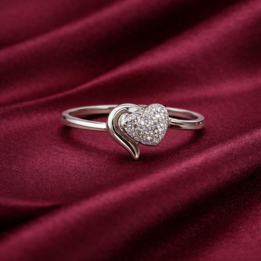 Silver heart-shaped ring with embedded stones on a burgundy fabric background
