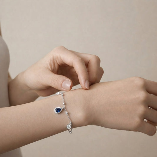 Person wearing a silver bracelet with a blue gemstone on a beige background