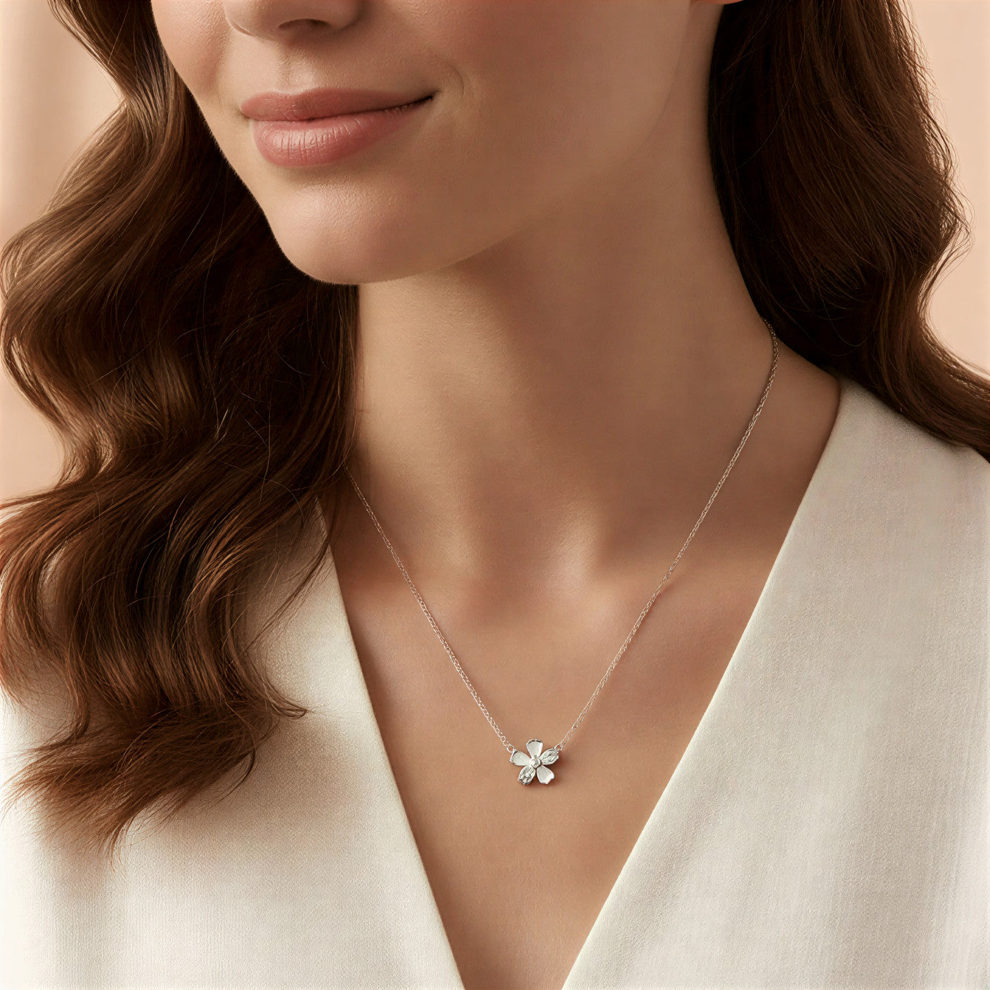 Close-up of a woman wearing a delicate necklace with a flower pendant against a neutral background