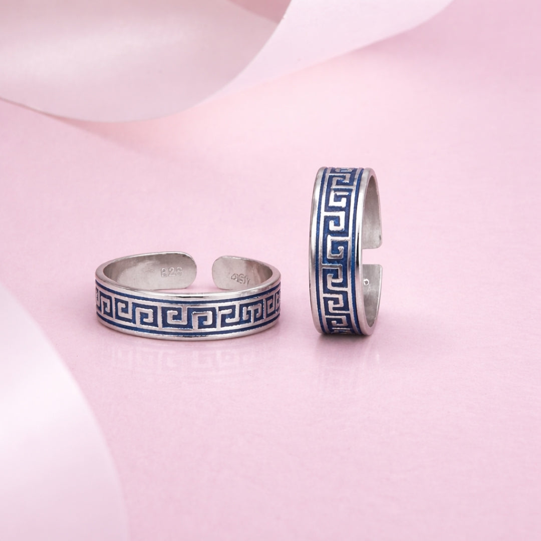Two silver bangles with blue patterns on a pink fabric background