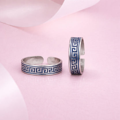 Two silver bangles with blue patterns on a pink fabric background