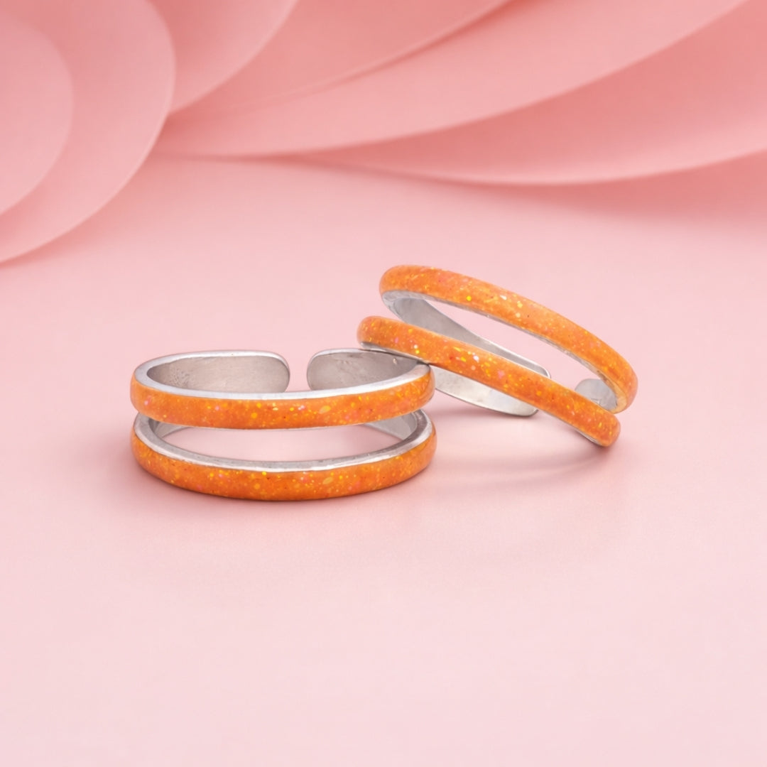 Three orange rings with silver bands on a pink background