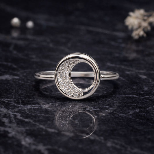Silver ring with circular design on a dark textured surface