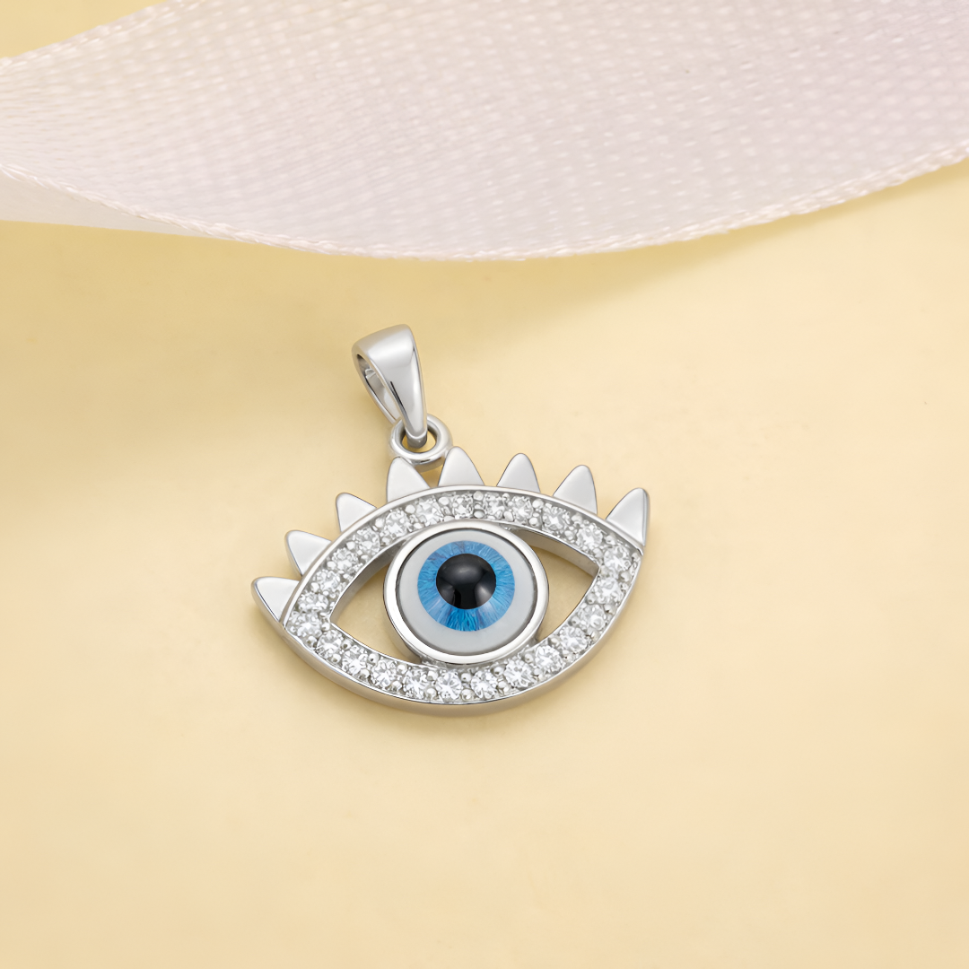 Silver eye-shaped pendant with a blue center on a beige background