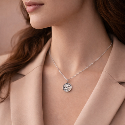 Silver necklace with a pendant worn by a person in a beige coat.