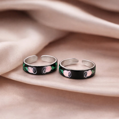Two silver rings with floral designs on a beige fabric background