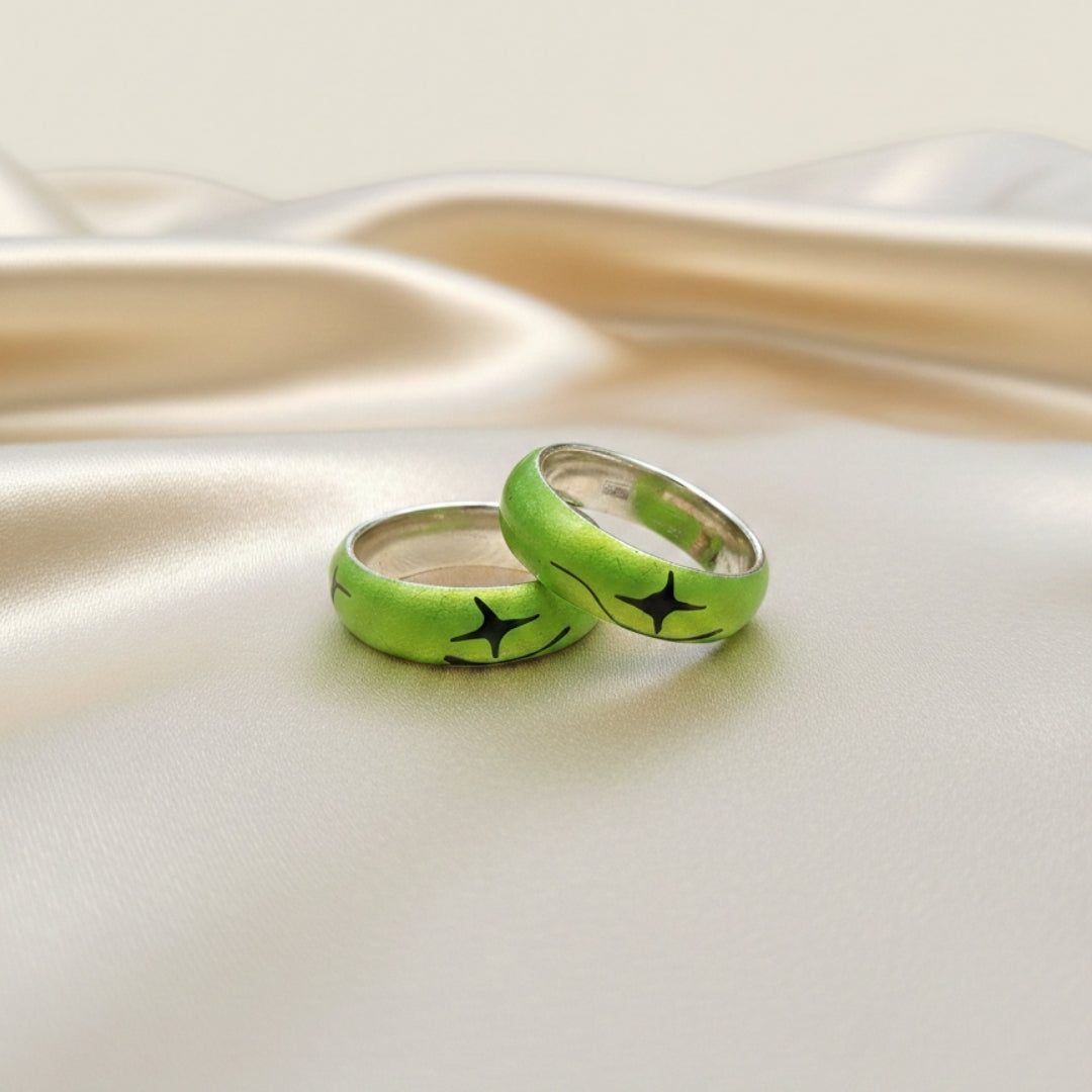 Two neon green rings with black star designs on a reflective surface.