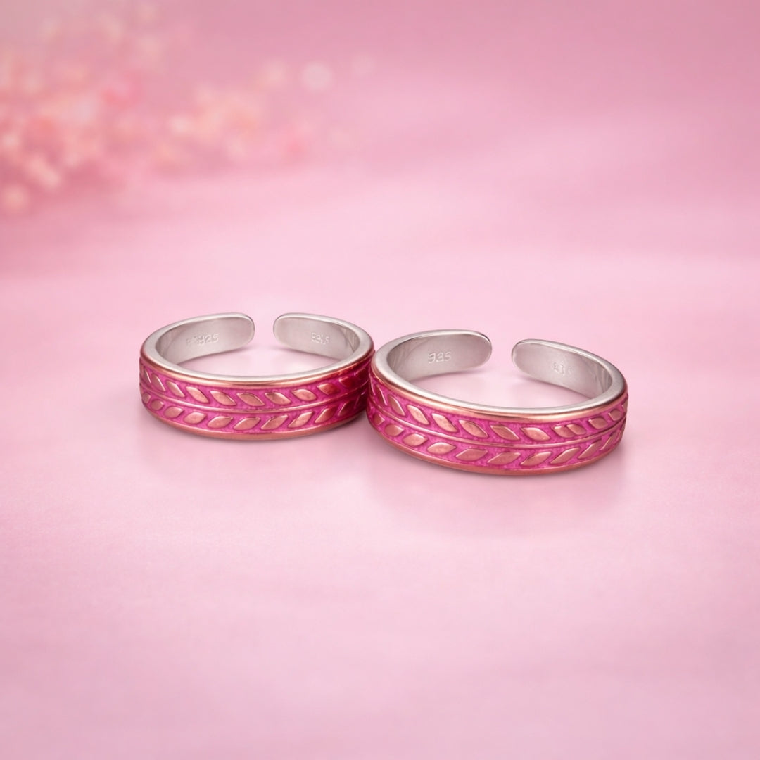 Two silver rings with pink accents on a pink background