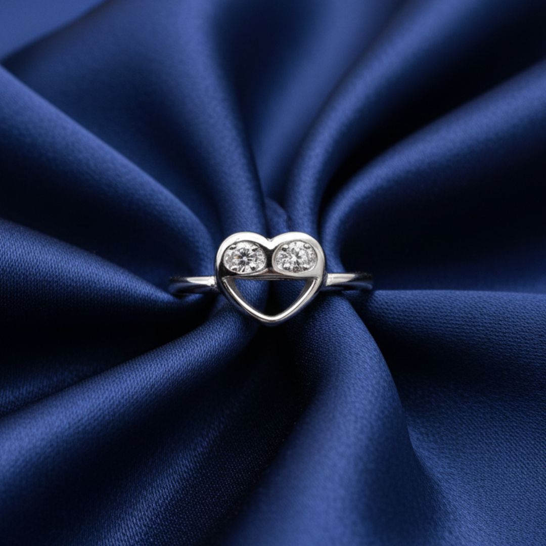 Silver heart-shaped ring with two diamonds on a blue satin background