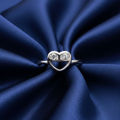 Silver heart-shaped ring with two diamonds on a blue satin background
