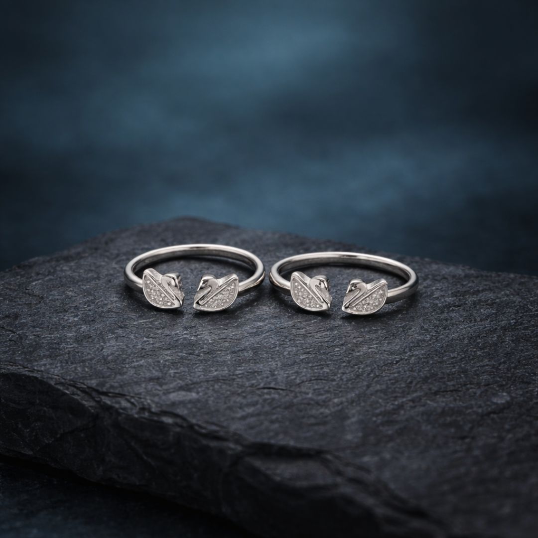 Two silver rings with leaf designs on a dark stone surface